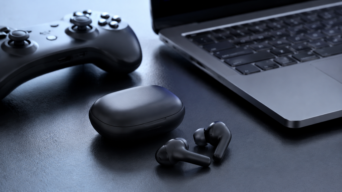 Low latency earbuds beside a game controller and laptop