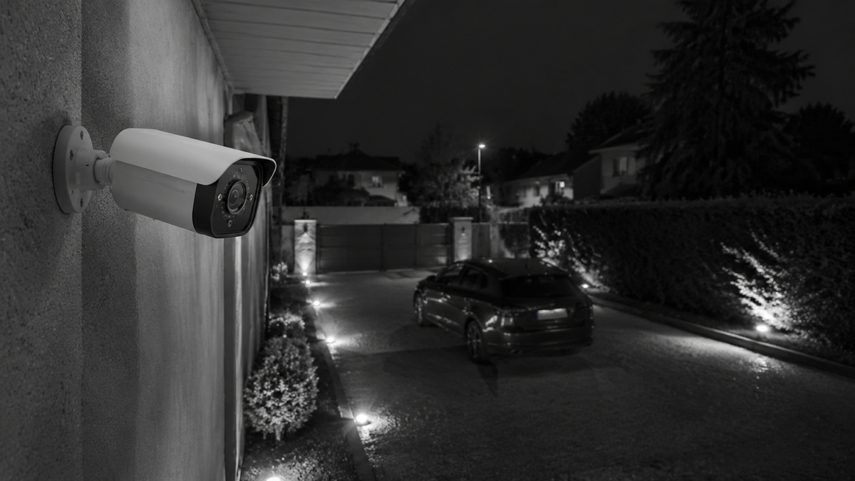 Unbranded night vision security camera monitoring a driveway after dark
