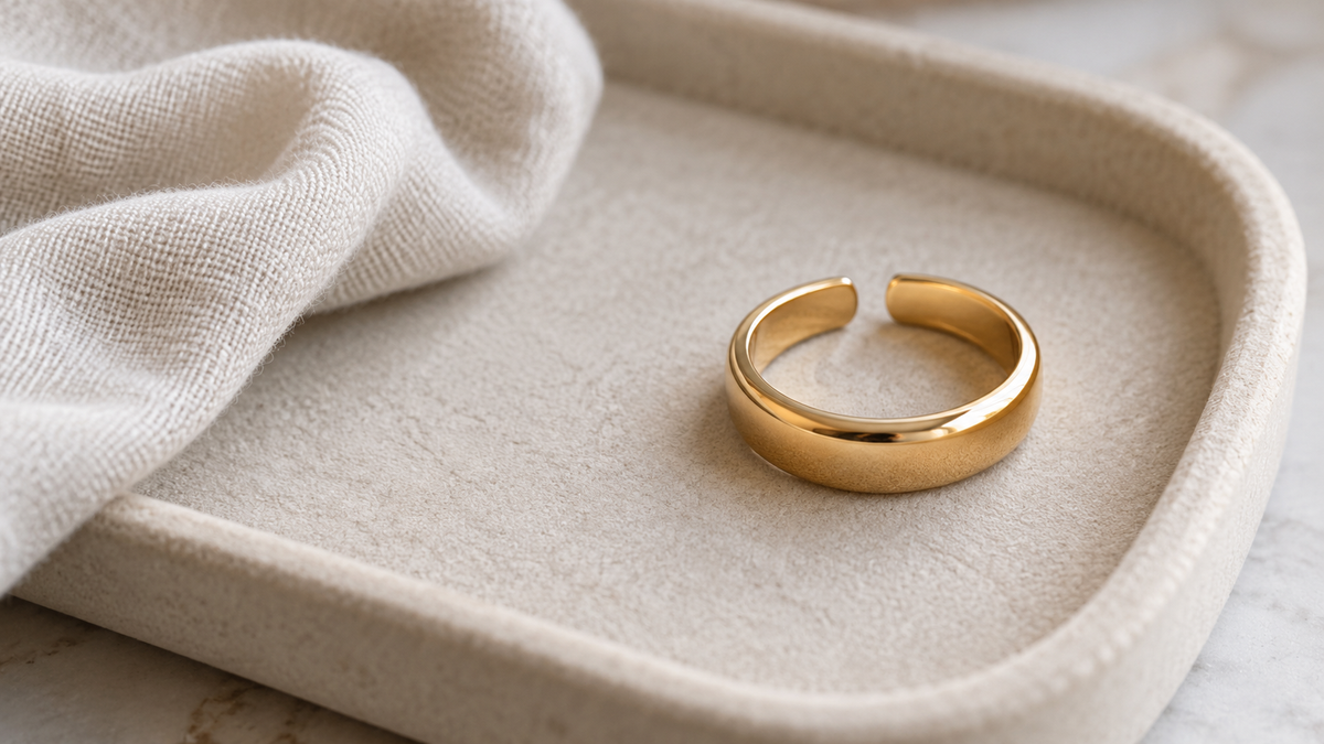 Open adjustable ring on a neutral jewelry tray beside a soft cloth